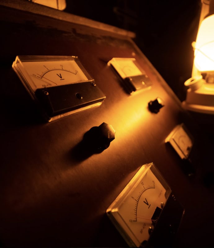 A dark room with vintage electrical meters and warm lighting, themed for escape room Miami.