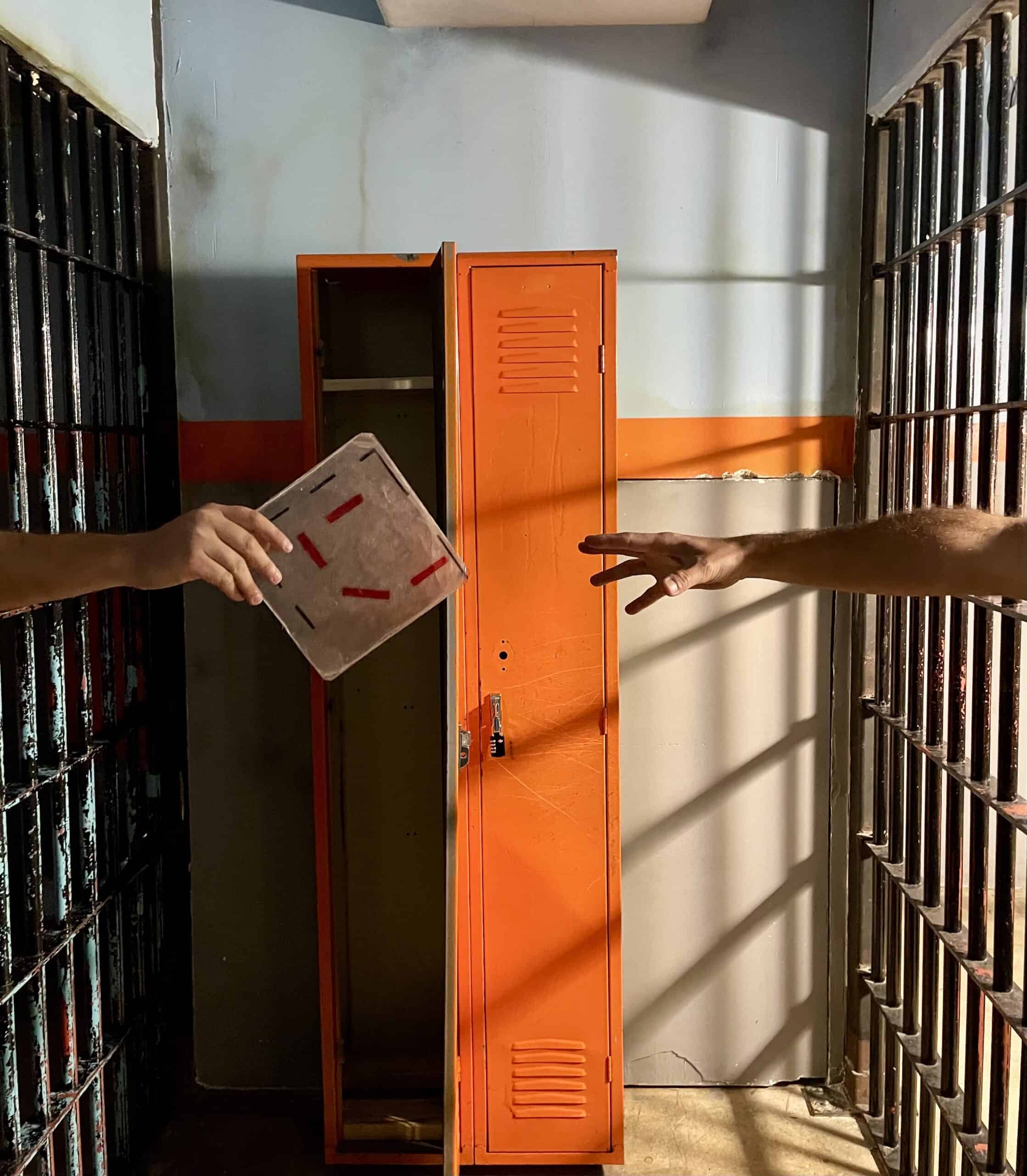 Escape room Miami scene with hands reaching for a puzzle piece near lockers at Fox in a Box.