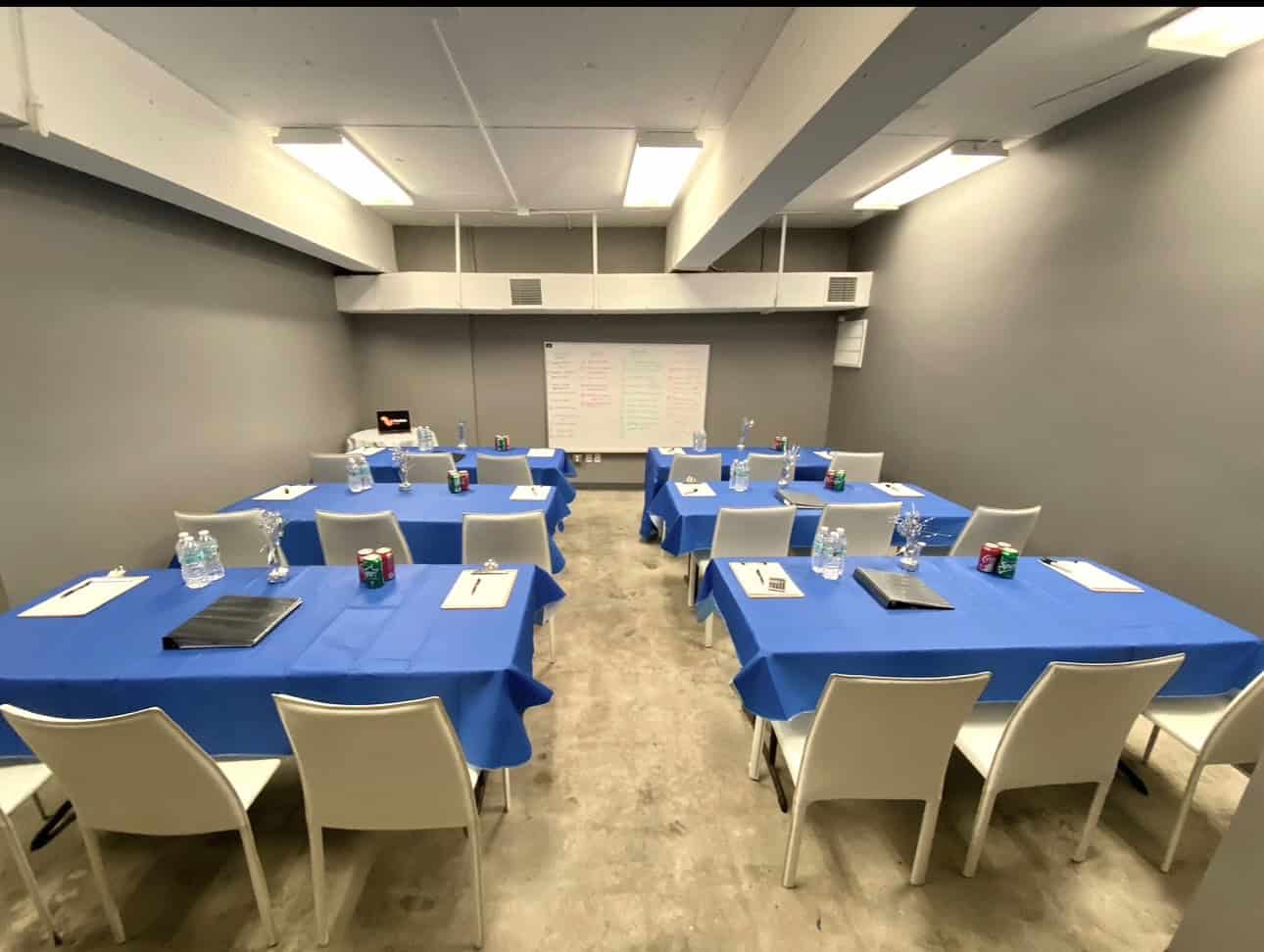 Escape room Miami training room with tables, chairs, and whiteboard for team activities.