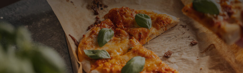 Delicious cheese and pepperoni pizza slice garnished with fresh basil leaves.