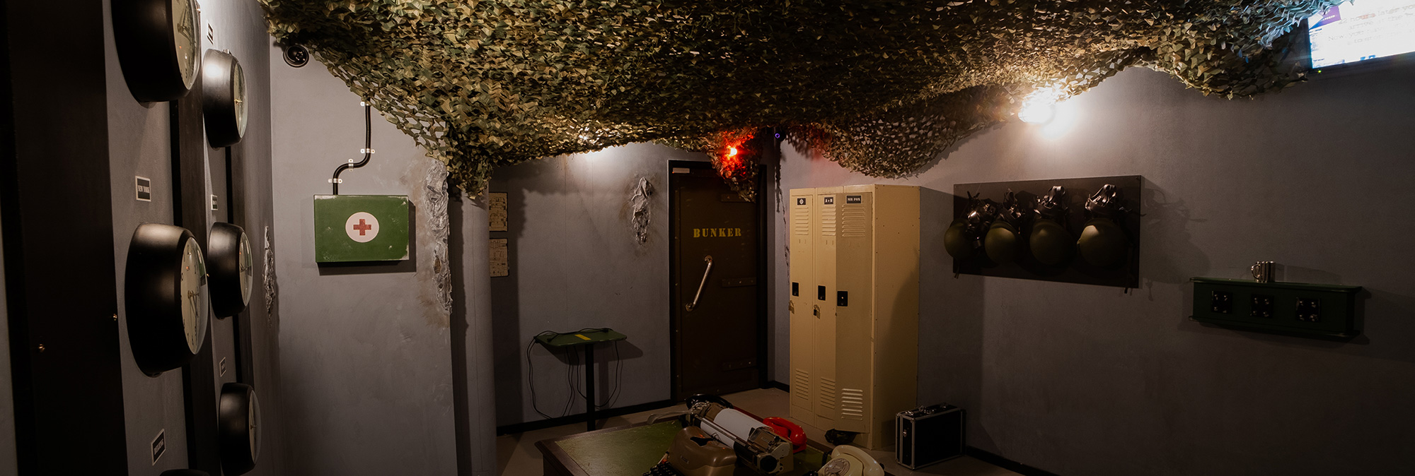 Escape room with military props, camouflage netting, and bunker door at Fox in a Box Stockholm.