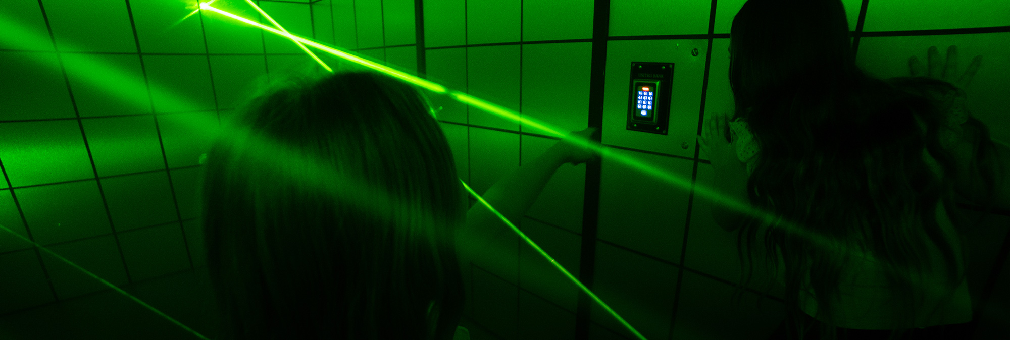 Laser tag game at escape room in Stockholm, including children in a laser maze with green laser beams, vibrant and immersive entertainment experience.