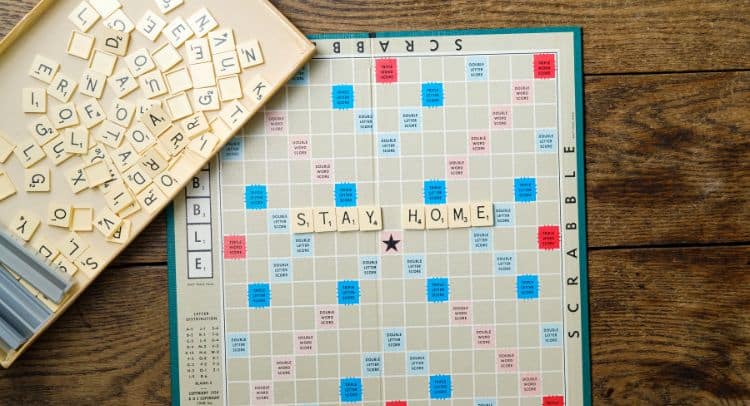 Addiction to Scrabble board game with tiles and letter cubes on wooden surface.