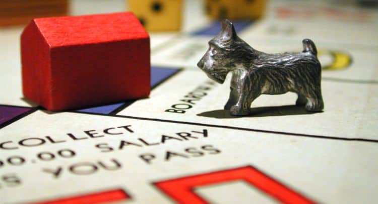 Red house and cat game pieces on Monopoly board, close-up.